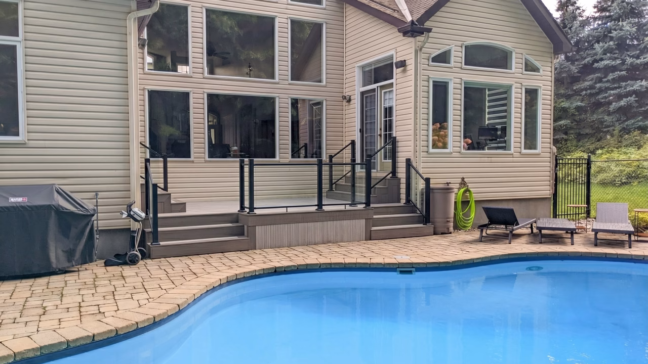Finished Fiberon Cabana deck with Latte trim, clear Fortress glass railing, and pool view in Barrhaven