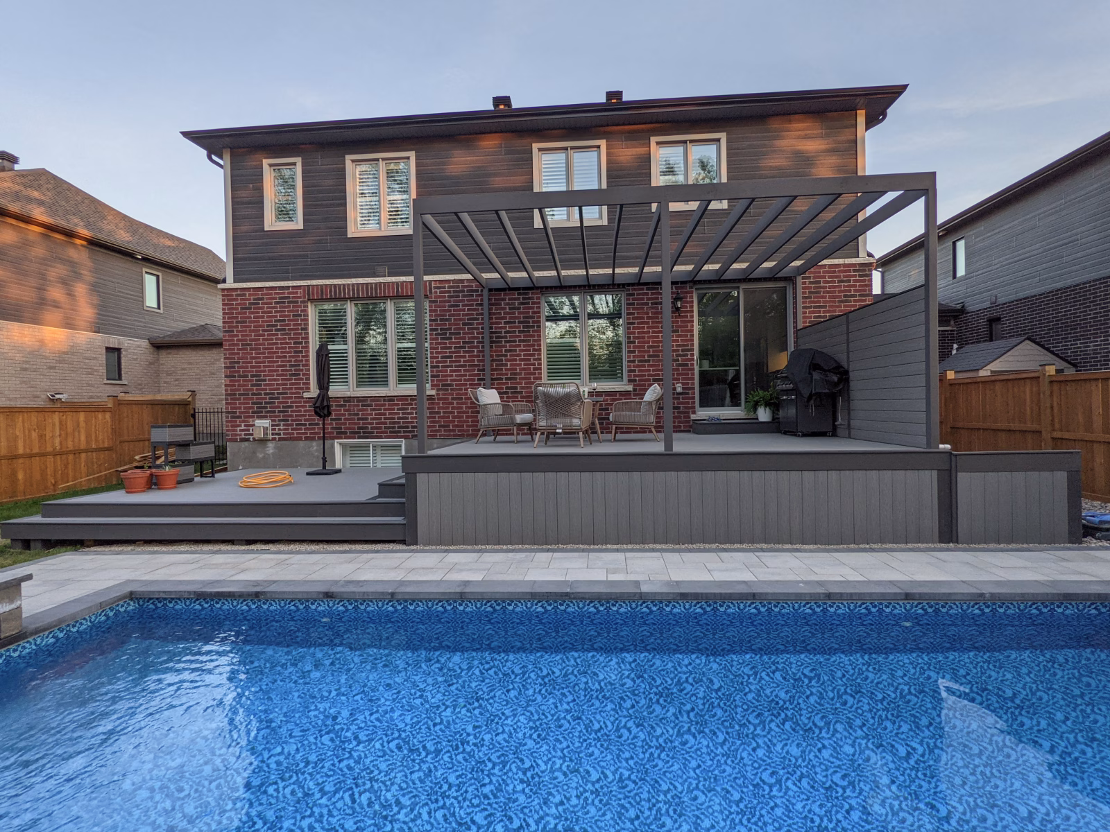 Finished Fiberon Cottage deck with Earl Grey trim, glass railing, pergola, and pool patio in Manotick