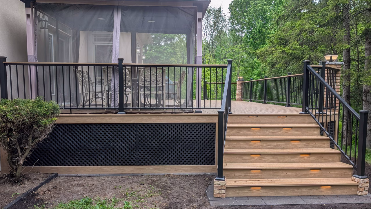 Finished Himalayan Cedar deck with Fortress railing, lit flared stairs, and stone-capped columns